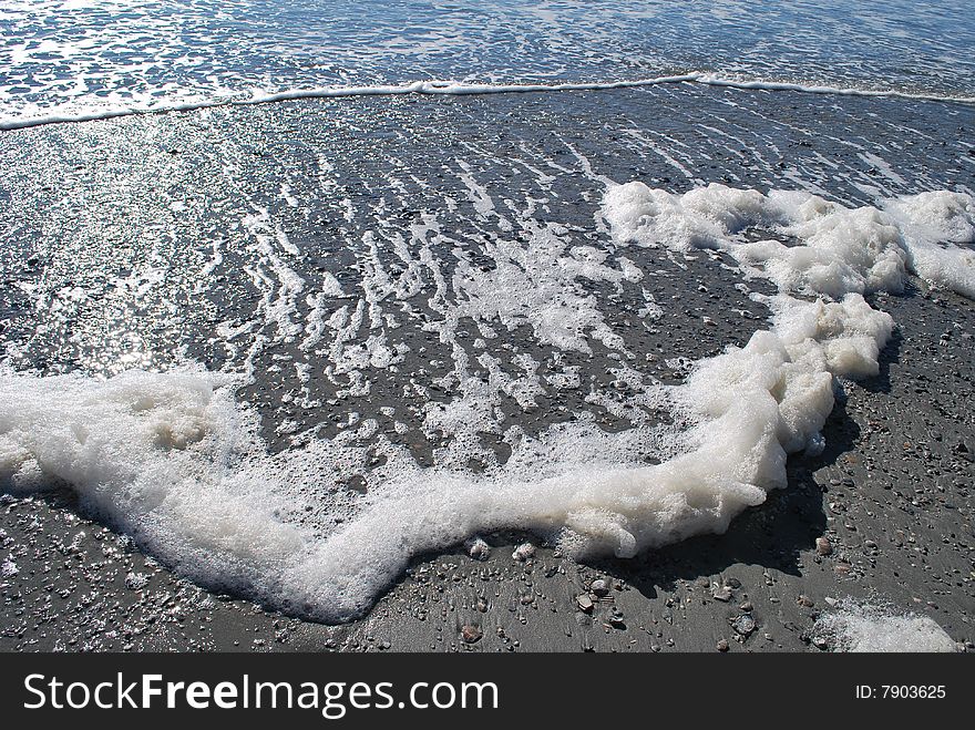 Waves rolling onto sand creating foam. Waves rolling onto sand creating foam