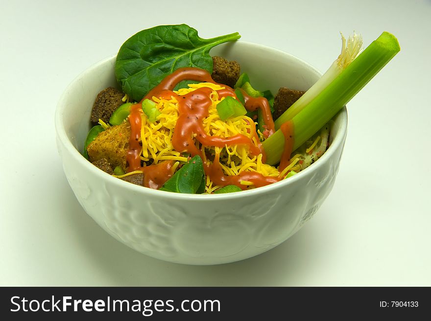 Bowl of salad covered with dressing, isolated on white