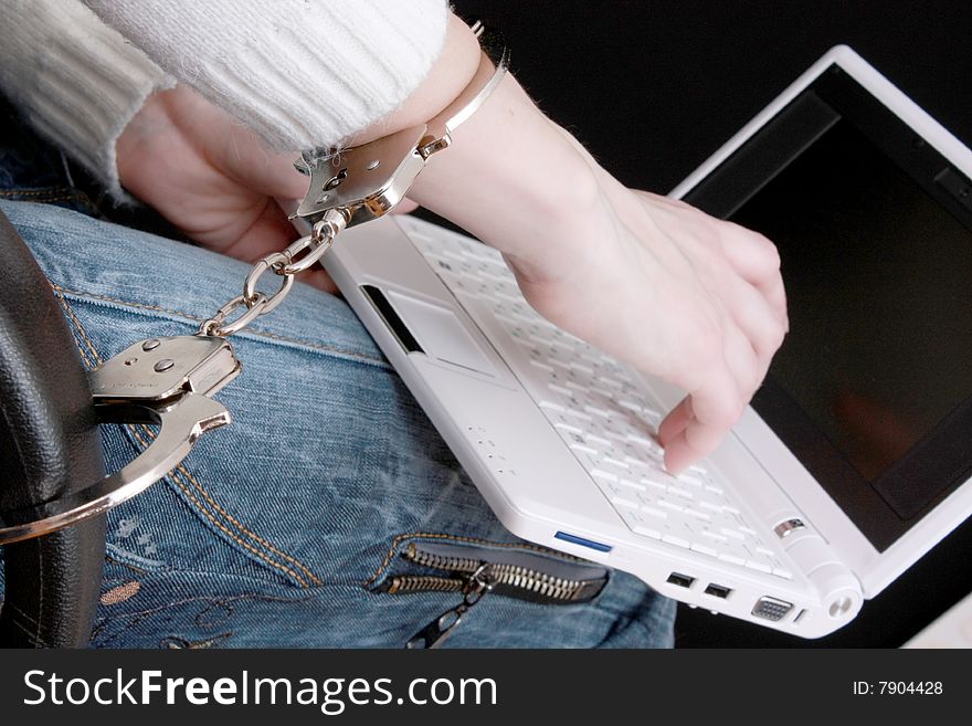 Hand in handcuffs on laptop on black background