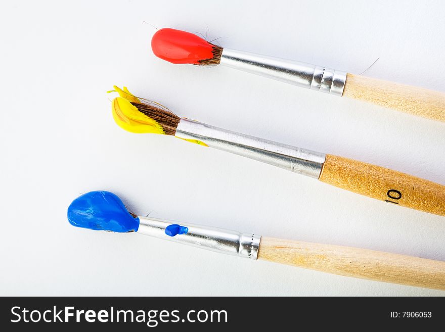 Stock photo: an image of a set of three paintbrushes with paints on them. Stock photo: an image of a set of three paintbrushes with paints on them