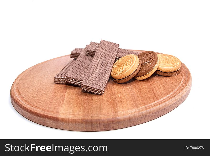 Wafers and cookie lie at the round board, isolated on a white background. Wafers and cookie lie at the round board, isolated on a white background.