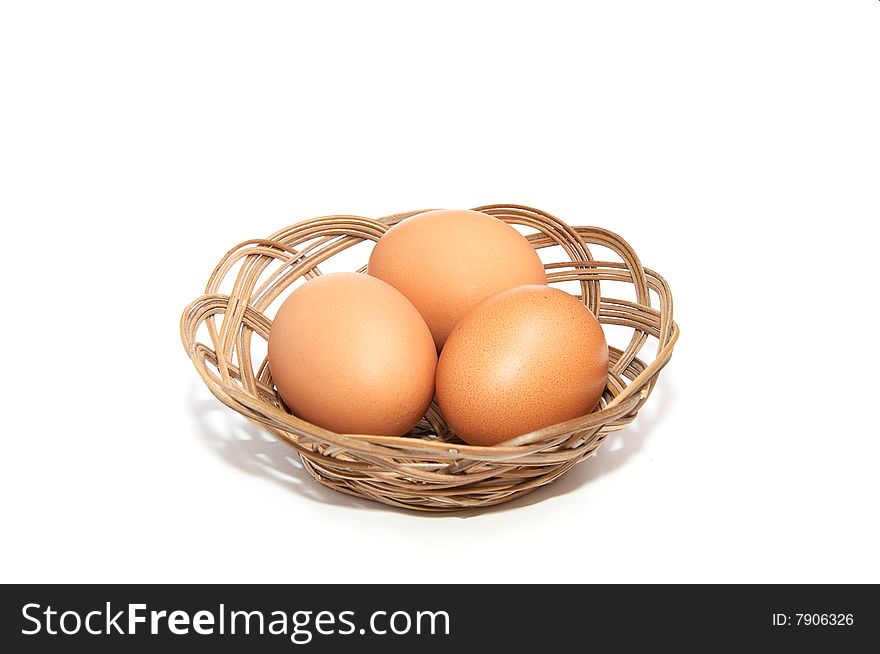 Three eggs in the wooden basket isolated on a white background. Three eggs in the wooden basket isolated on a white background.