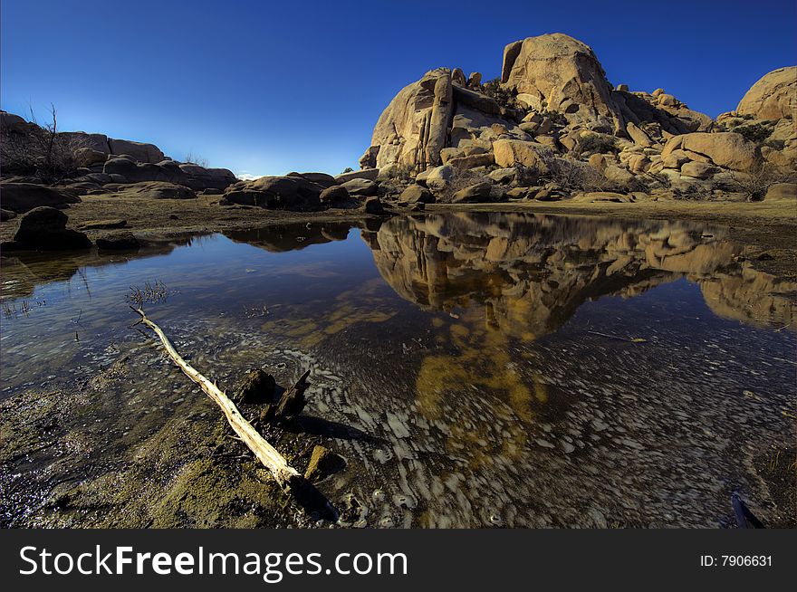 A mirror lake found at barker's dam in Joshua Tree Natural park in southern california. There's a bark in the foreground. A mirror lake found at barker's dam in Joshua Tree Natural park in southern california. There's a bark in the foreground