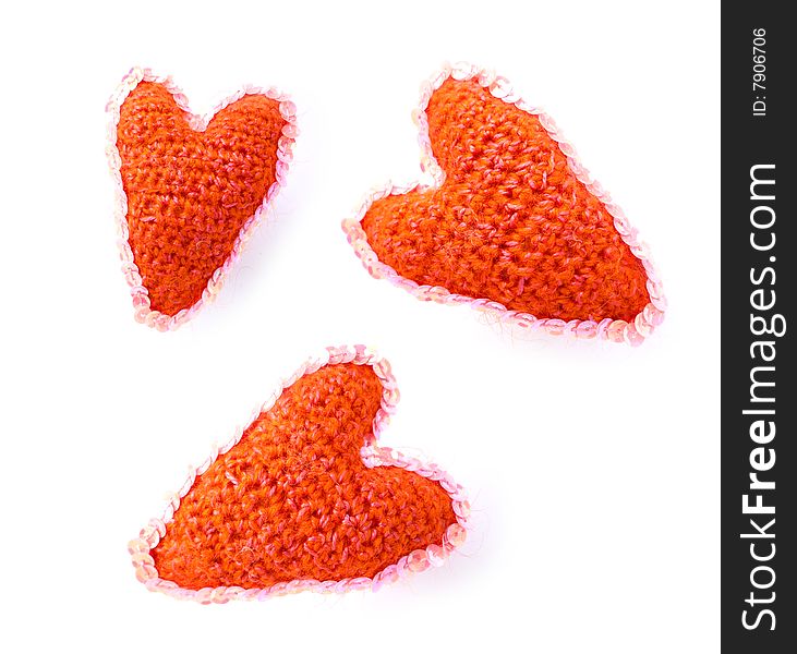 Three red hearts from a wool of manual work on a white background with an ornament. Three red hearts from a wool of manual work on a white background with an ornament