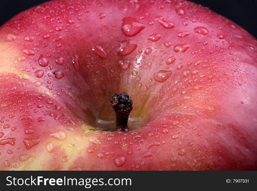 A close up of a red apple covered in dew.