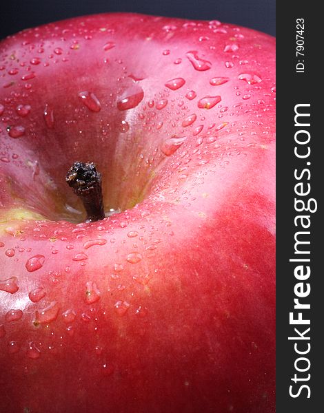 A close up of a red apple covered in dew.