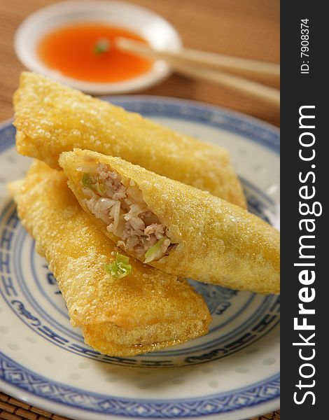 Three spring rolls with dip on plate