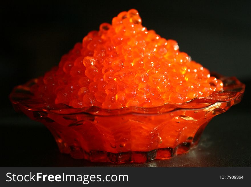 Dish with red  caviar is on a table