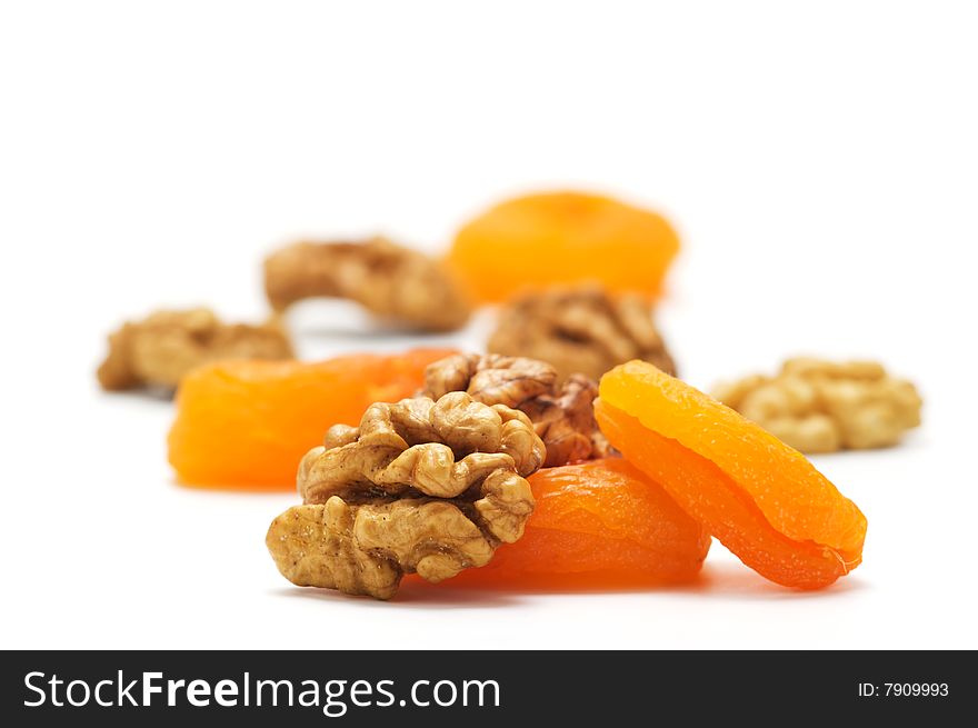 Dried apricots and walnuts isolated on a white background. BAckground blurry.