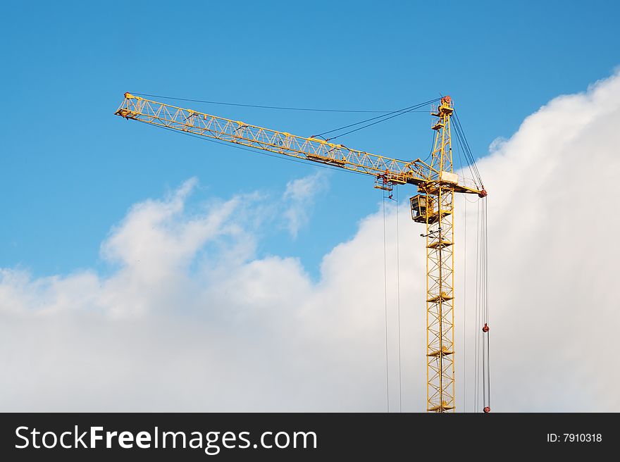 Yellow crane on blue sky with clouds