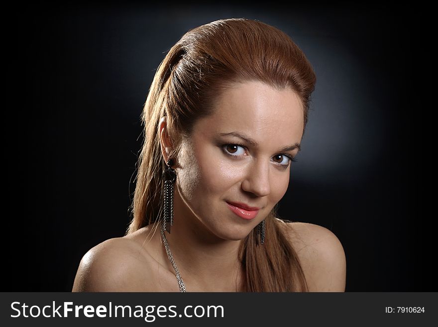 Portrait of pretty young smiling girl on dark background