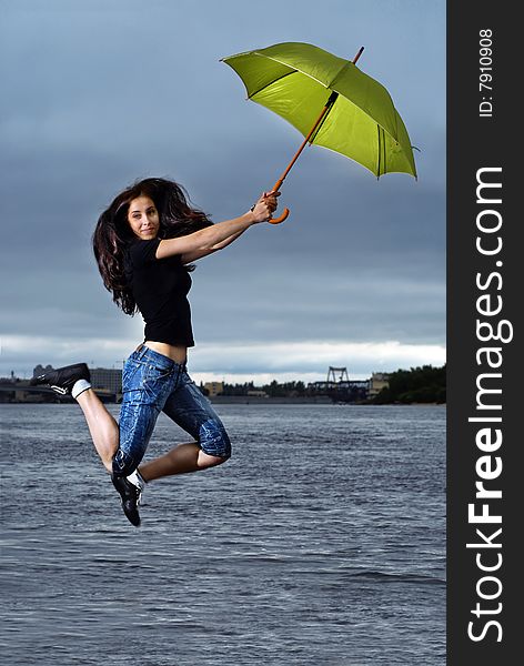 Girl jumping against sky and water with umbrella. Girl jumping against sky and water with umbrella