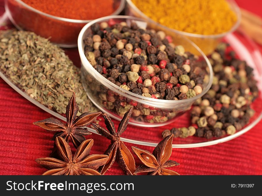 Spices in small glass bowl on red background