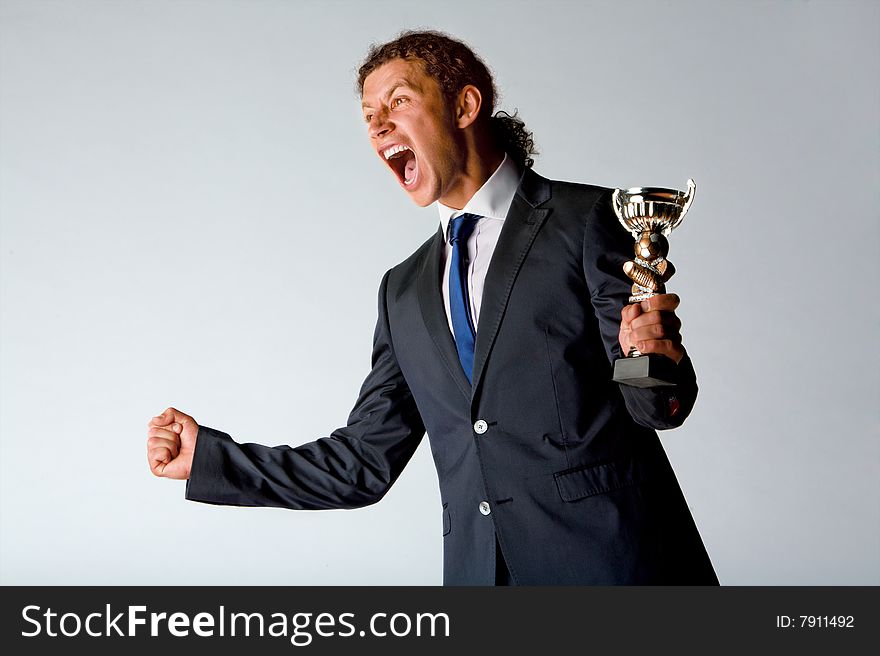 Half body portrait of successful sportsman holding trophy and shouting in celebration, white background.