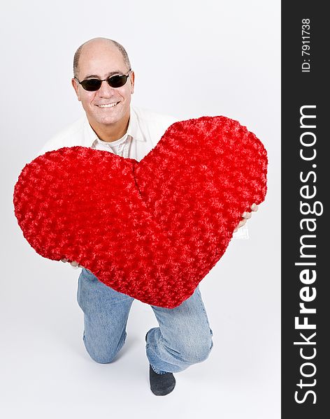 A handsome Latin man holding a big red heart. A handsome Latin man holding a big red heart.