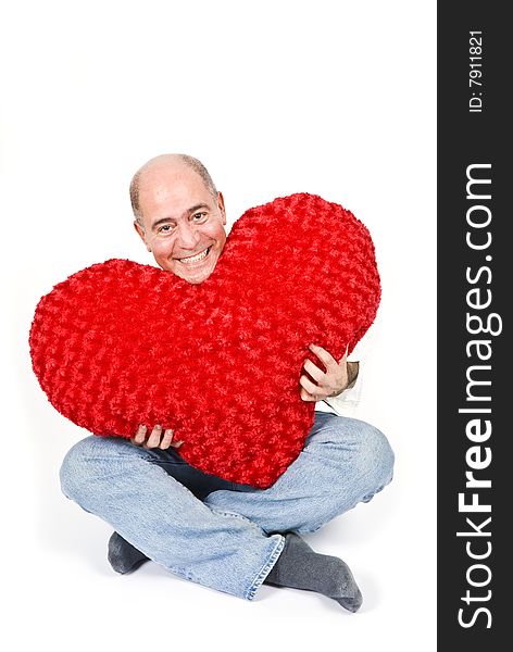 A handsome Latin man sitting holding a big red heart. A handsome Latin man sitting holding a big red heart.