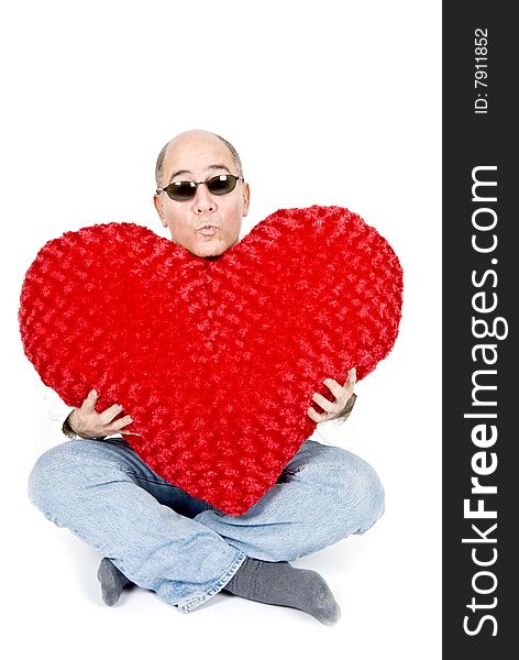 A handsome Latin man sitting holding a big red heart. A handsome Latin man sitting holding a big red heart.