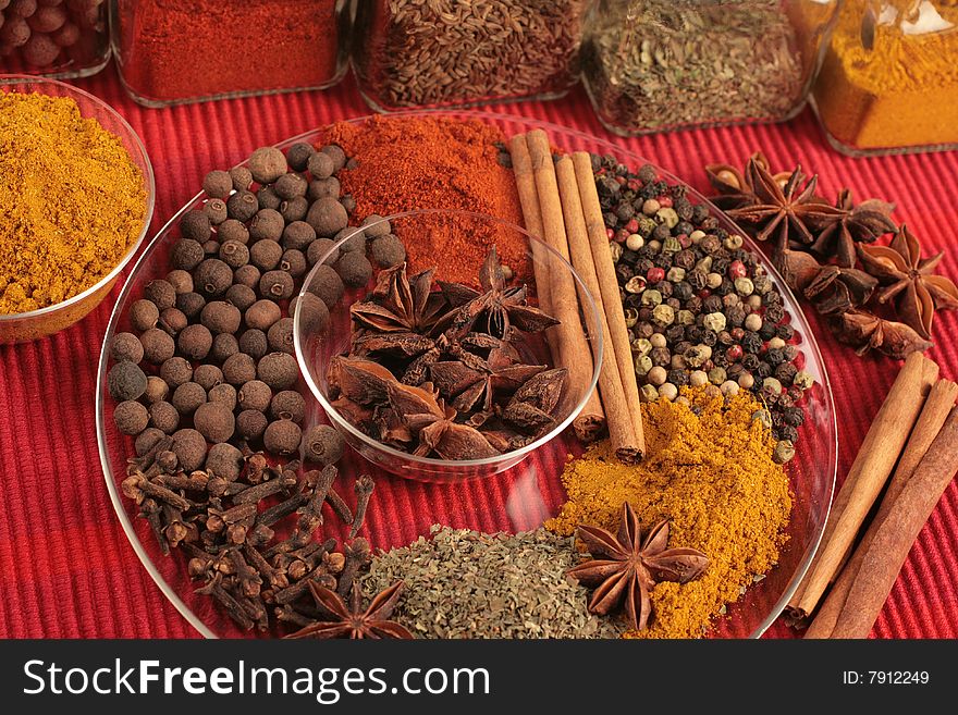 Spices on glass plate on red background