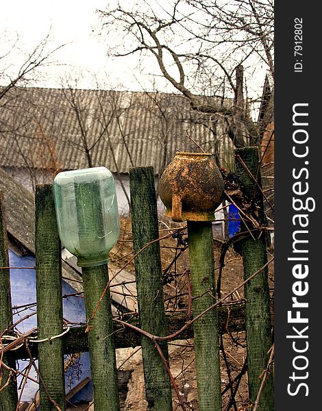 Rural scenery: fence with jars trees and house
