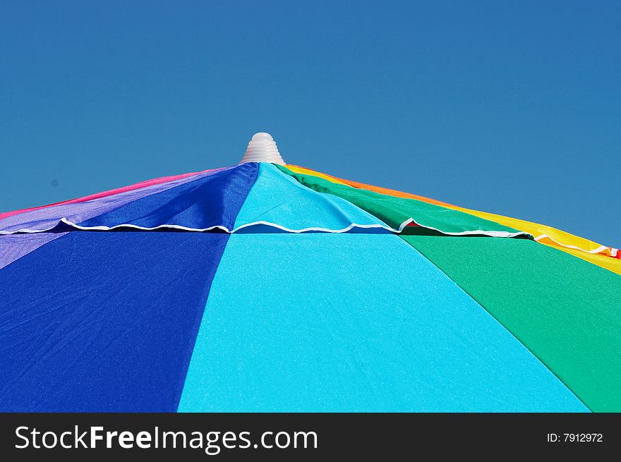 Bright colorful beach umbrella against blue sky