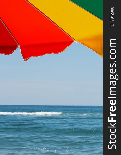 Bright colorful beach umbrella against blue sky and ocean