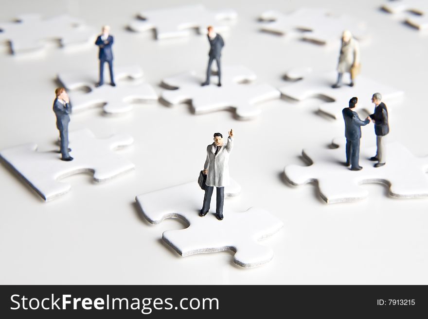Businessman figurines placed on puzzle pieces. Businessman figurines placed on puzzle pieces