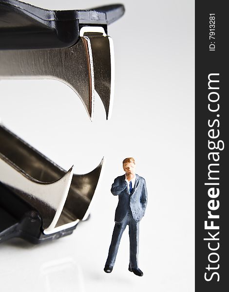 Businessman figurines standing next to a staple remover. Businessman figurines standing next to a staple remover