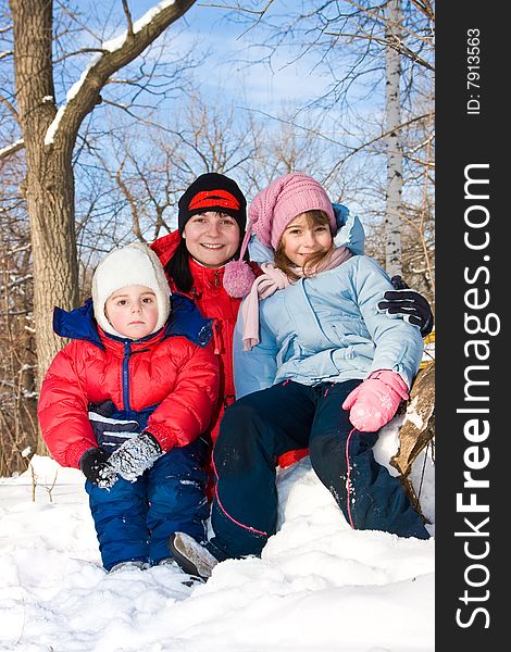 Mum with the son and a daughter sit on snow in park. Mum with the son and a daughter sit on snow in park.