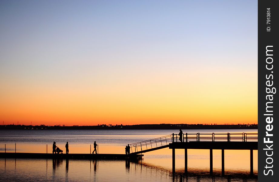 A view of silhouetted people walking on a pier