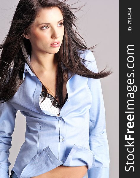 Glamour Portrait of woman wearing blue shirt on grey background.