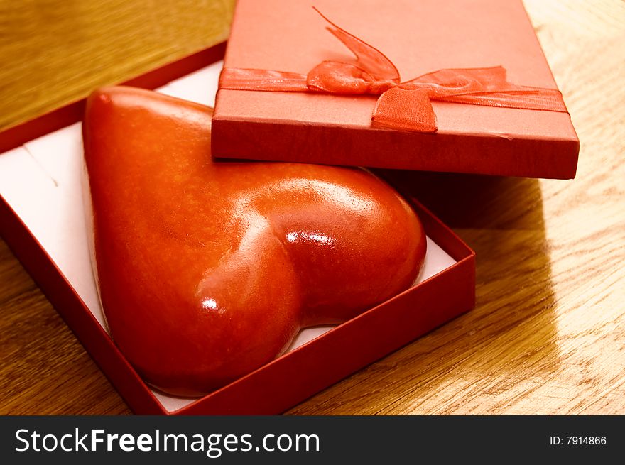 Heart in gift box over wooden background