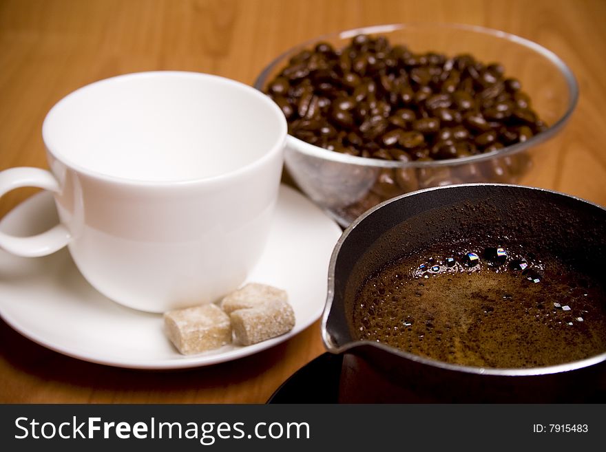 Cup, coffee, sugar and beans in glass bowl on wooden table