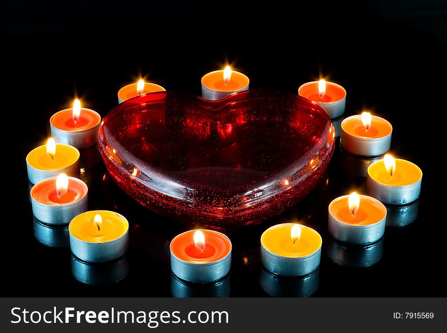 Big red heart, surrounded small candles light, on a black background. Big red heart, surrounded small candles light, on a black background.