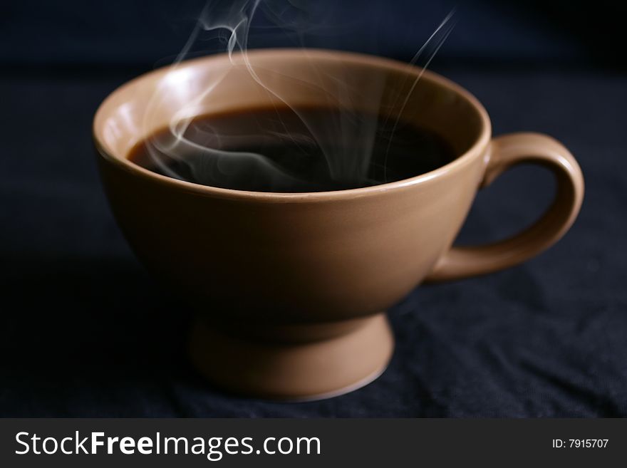 Cup with hot drink on a black background.