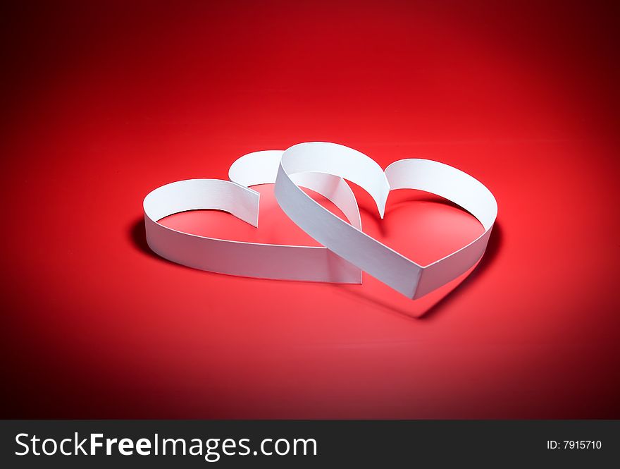 Intertwining of two hearts with center spot light, on red background. Focus on a center. Intertwining of two hearts with center spot light, on red background. Focus on a center.