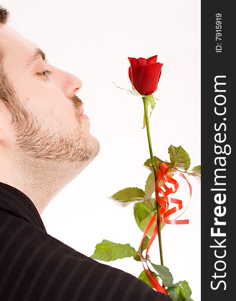 Young man holding and admiring a red rose. Young man holding and admiring a red rose