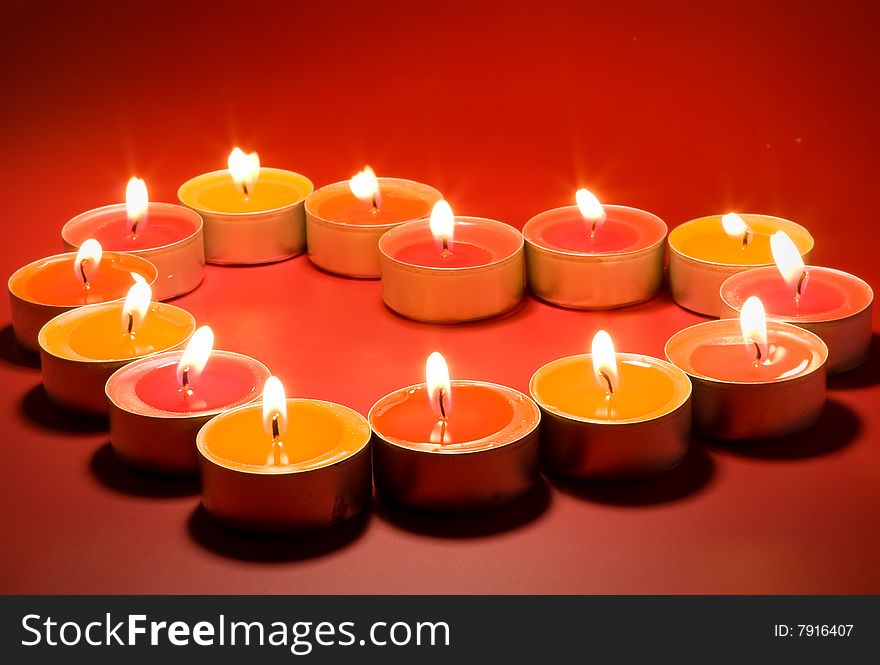 Small light candles, in heart form on red.