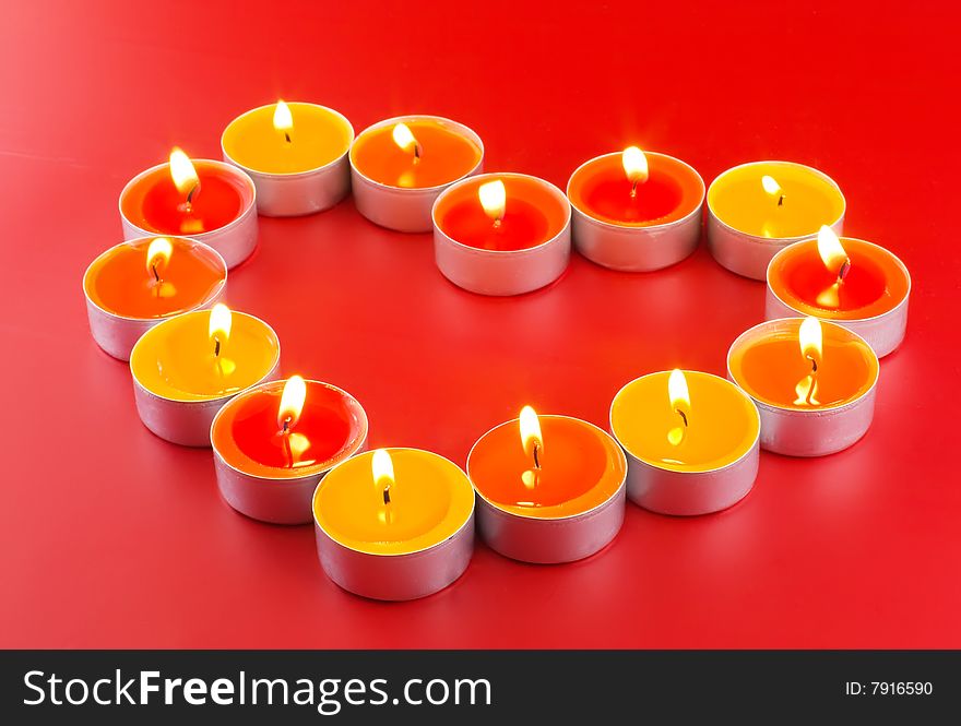 Small light candles, in heart form on a red background. Small light candles, in heart form on a red background.