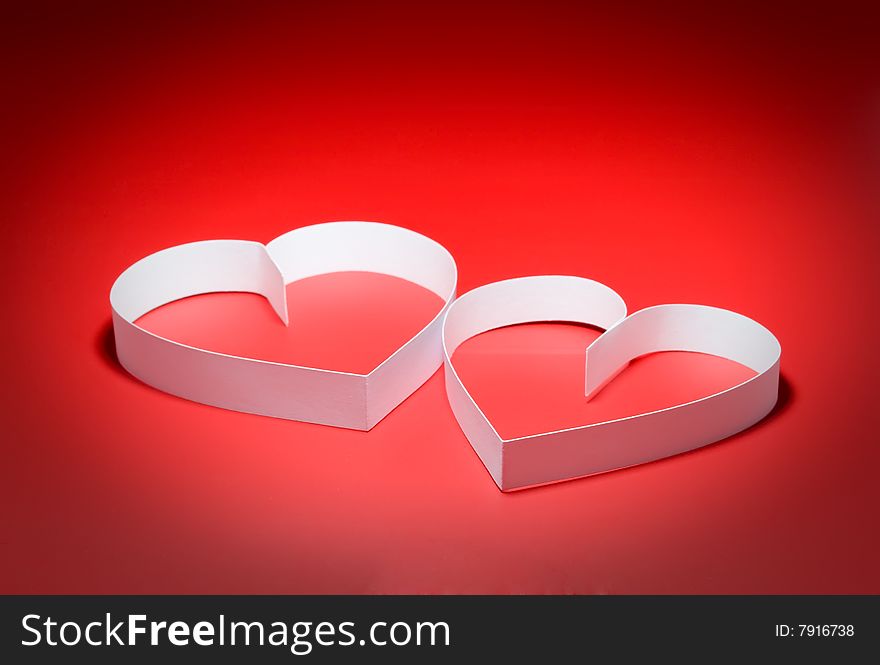 Intertwining of two hearts with center spot light, on red background. Focus on a center. Intertwining of two hearts with center spot light, on red background. Focus on a center.