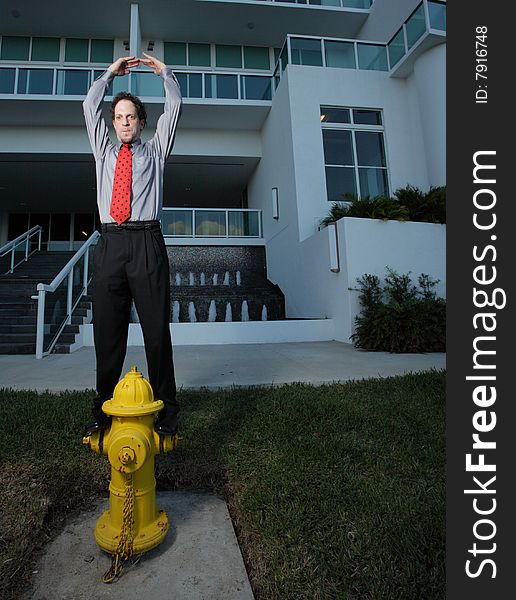 Businessman standing on a fire hydrant and pretending to be a ballerina. Businessman standing on a fire hydrant and pretending to be a ballerina