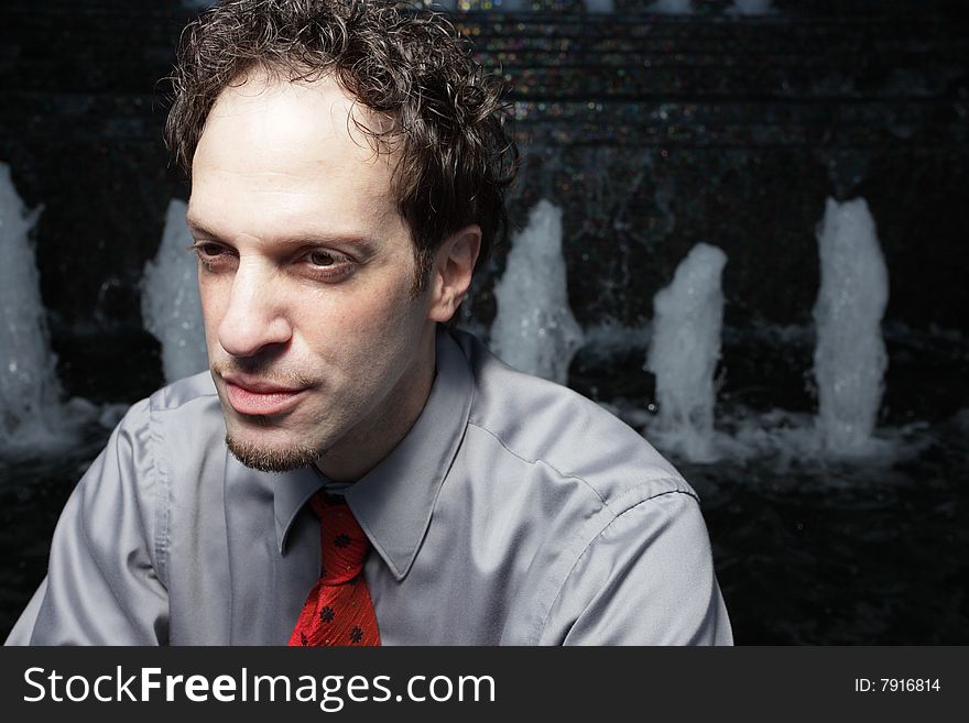 Businessman sitting by an abstract water fountain. Businessman sitting by an abstract water fountain