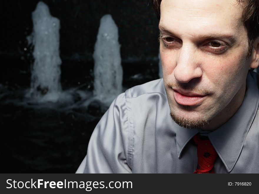 Businessman sitting by an abstract water fountain. Businessman sitting by an abstract water fountain