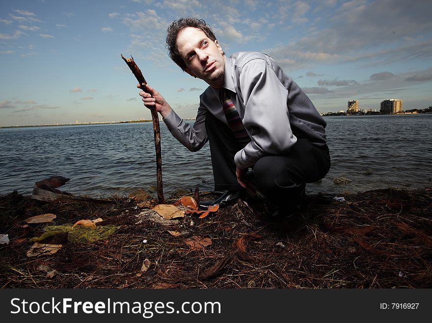 Businessman squatting and holding a stick while looking over his shoulder. Businessman squatting and holding a stick while looking over his shoulder