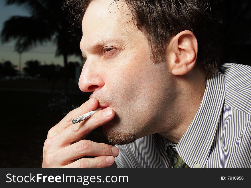 Businessman taking a puff of his cigarette. Businessman taking a puff of his cigarette