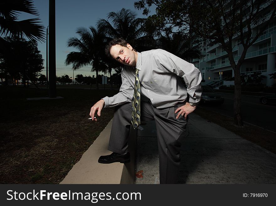 Businessman in an unusual pose while holding a cigarette in his hand. Businessman in an unusual pose while holding a cigarette in his hand