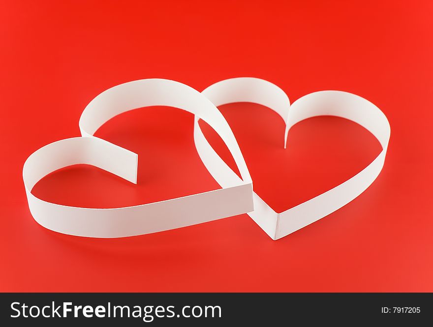 Two hearts,on red background,  laying  one on the another.Focus on the front side. Two hearts,on red background,  laying  one on the another.Focus on the front side.