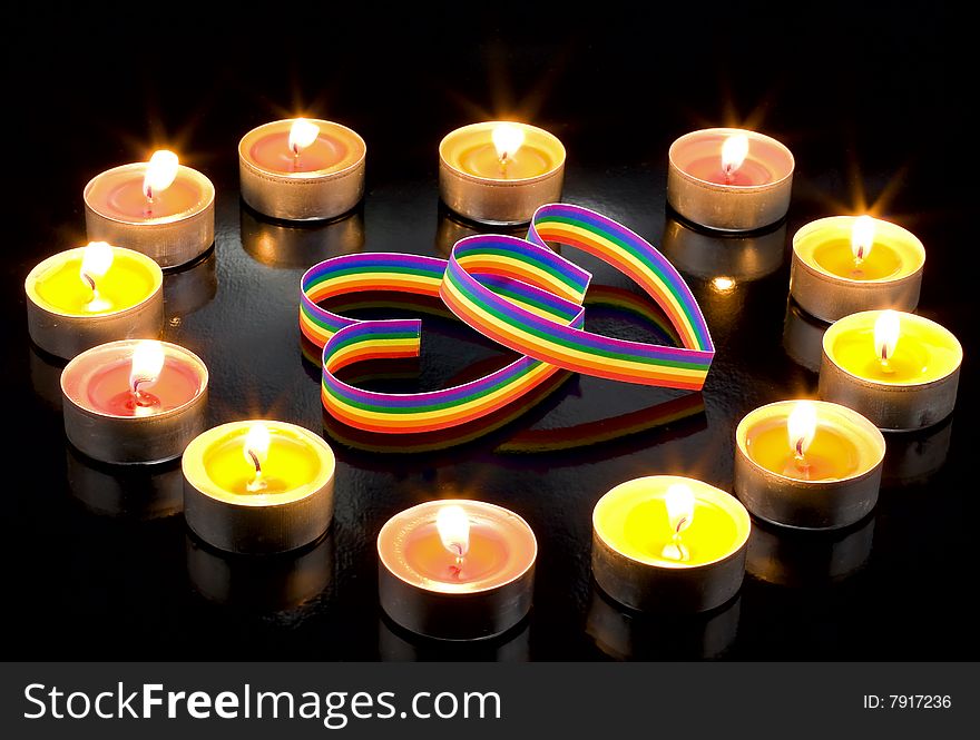 Two gay-colour  hearts, surrounded small candles light, on a black background. Two gay-colour  hearts, surrounded small candles light, on a black background.