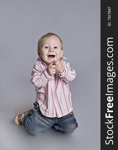 A little boy smiles upright on knees