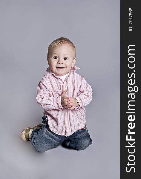 A little boy smiles upright on knees