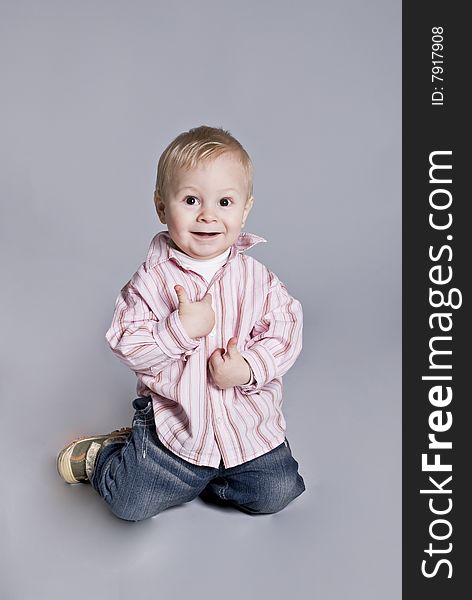 A little boy smiles upright on knees